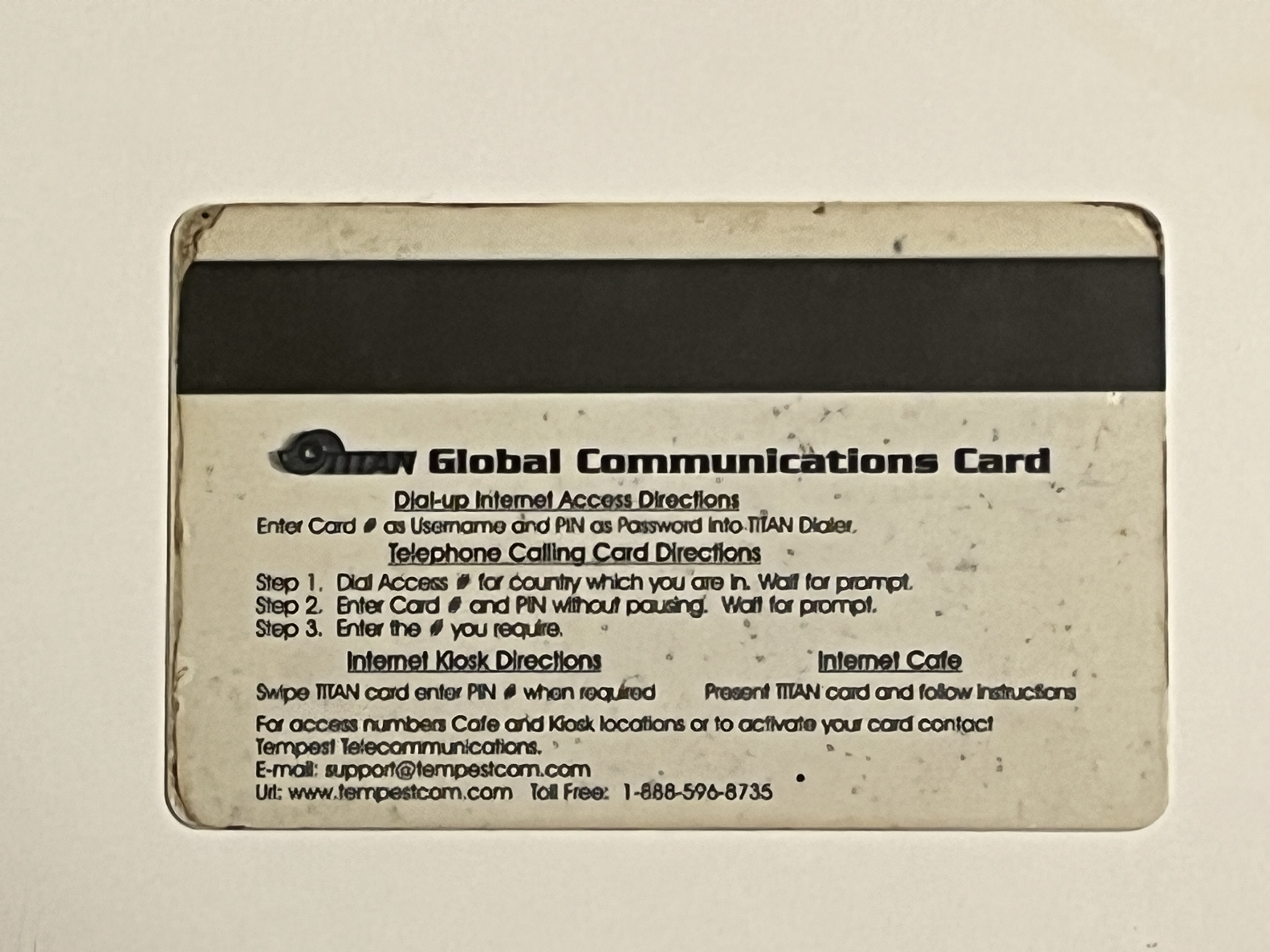 Reverse of the TITAN Global Communications Card showing a magnetic stripe and printed directions for dial-up, telephone calling, Internet kiosk, and cyber cafe use, with Tempest Telecommunications contact details